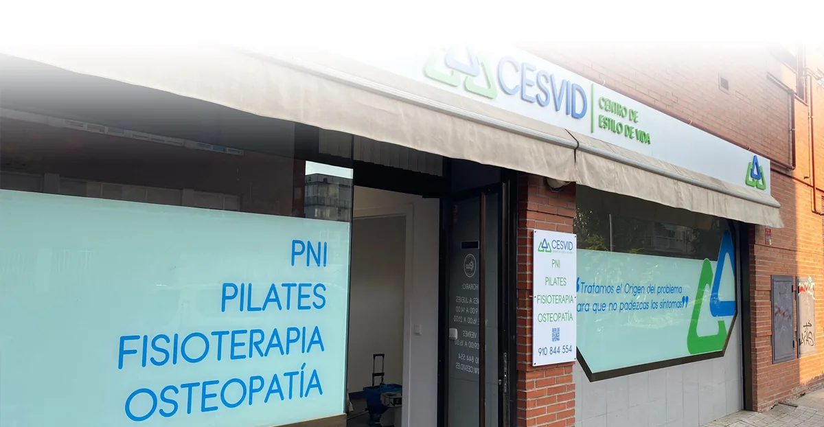 Fachada de CESVID: el rótulo con el logo, el toldo y el escaparate con PNI, pilates, fisioterapia y osteopatía